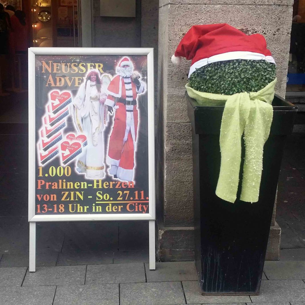 Ein Kundenstopper in Neuss zeigt die Weihnachts-Giganten von Corpus Titanium für den kommenden Neusser Advent.